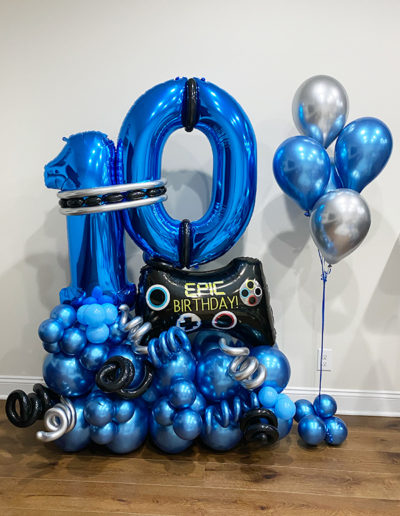 Blue and black balloon garland shaped like the number 80 with "epic birthday" sign and additional standalone silver balloons.