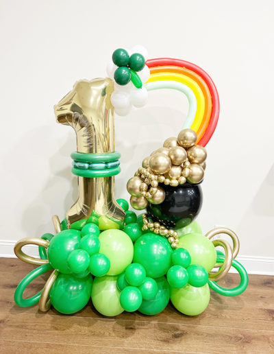 A balloon sculpture in Omaha featuring a golden horse, balloons arranged like green grapes, balloons shaped as golden orbs, and a balloon arch at the top.