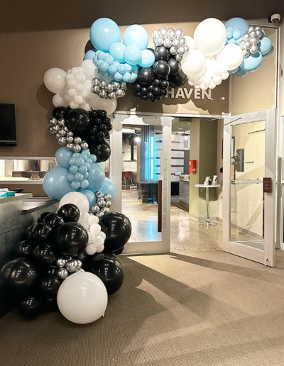 Office entrance decorated with a balloon arch of blue, white, and black balloons, with a sign labeled "haven" above the door.