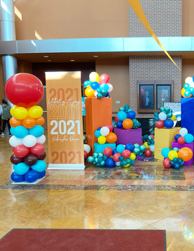 Decorative setup in a lobby for a 20-year anniversary event from 2001 to 2021 with a balloon garland and large numeral displays.