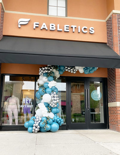 Exterior of a Fabletics store in Omaha, Nebraska, with a decorative arch of blue and white balloons around the entrance.